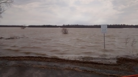 floodwaters over road, with sign warning of possible water on road